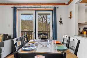 Enjoy meals in this dining area with a table for four, glassware, and a beautiful view of the balcony.