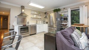 Een moderne keuken met roestvrijstalen apparatuur, witte kasten en een eethoek met een tafel en stoelen.