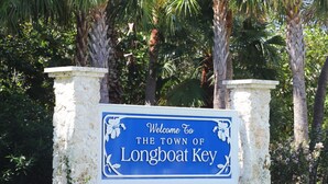 Welkomstbord voor de plaats Longboat Key, met een blauwe achtergrond, witte tekst en decoratieve bloemdetails.