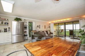 Una cocina moderna con una mesa de comedor de madera, electrodomésticos de acero inoxidable y un puerta corrediza de vidrio a un balcón.
