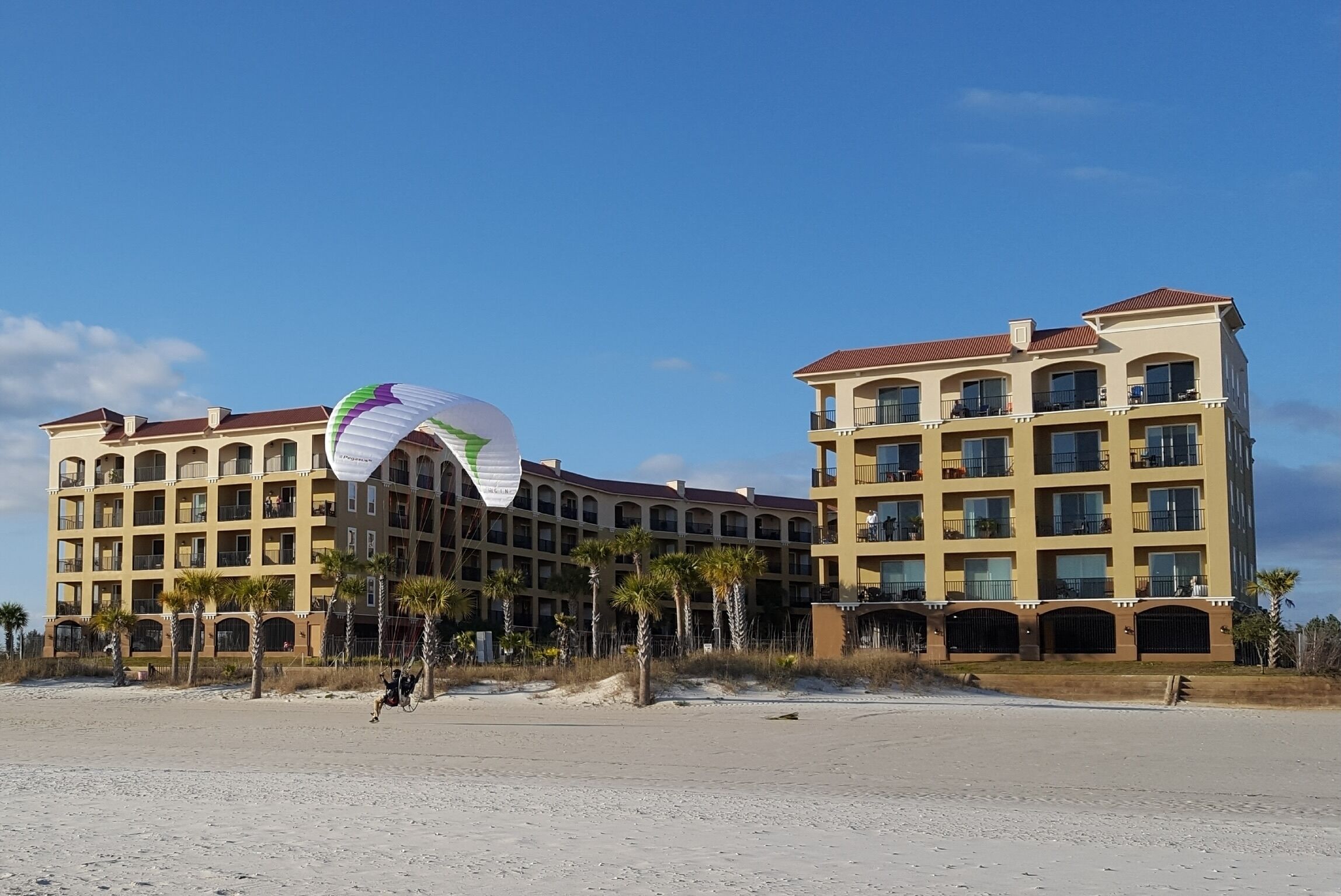 A multi-story hotel with balconies and a beach view.