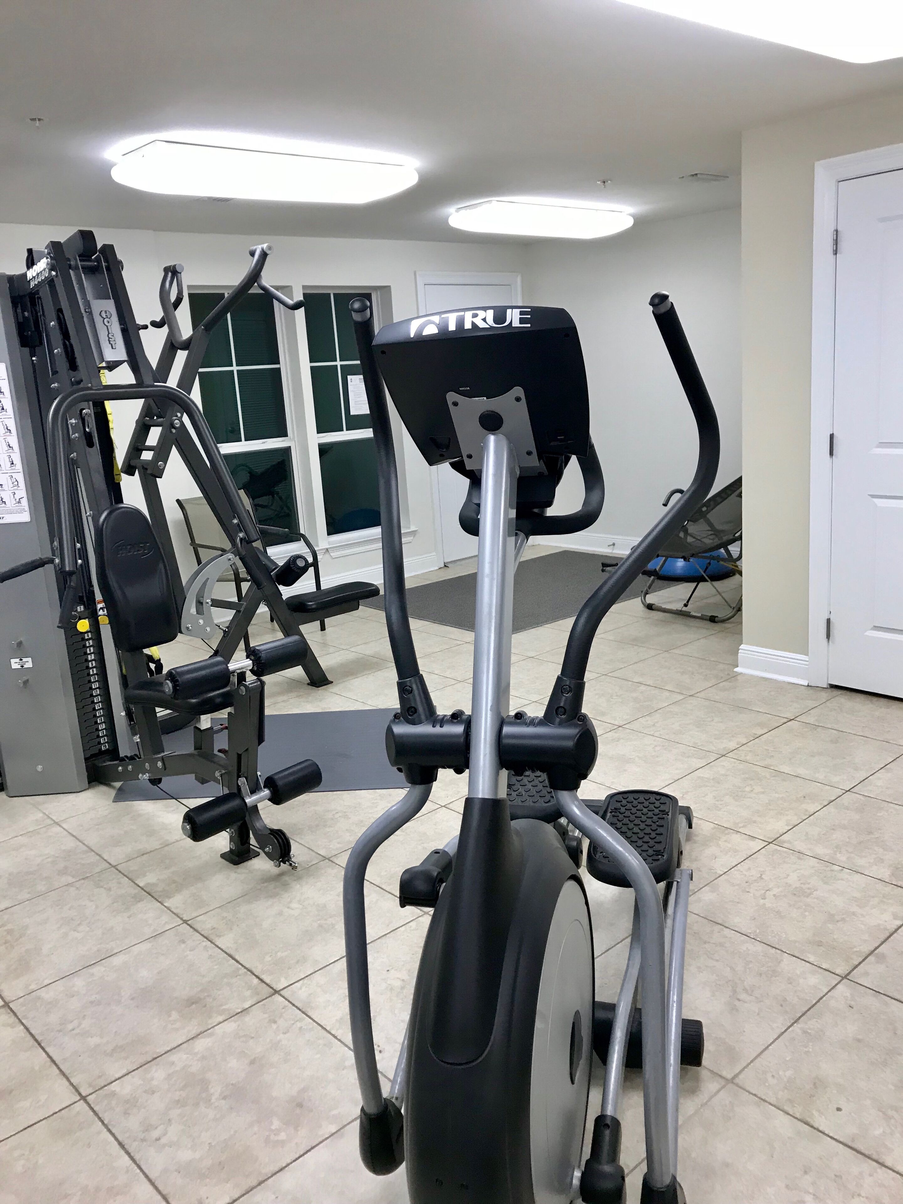 A gym with various exercise equipment, including an elliptical machine and weight machines.