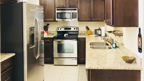 A kitchen with dark wooden cabinets, stainless steel appliances, and a granite countertop.
