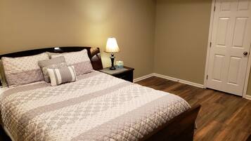 A bedroom with a bed, nightstand, lamp, and a door.