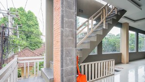 A modern interior with a staircase, a balcony, and a view of greenery outside. - Kememai Hostel (Ubud)