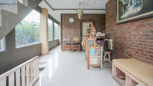 A spacious room with a staircase, a wooden bench, a desk, and a large window. - Kememai Hostel (Ubud)
