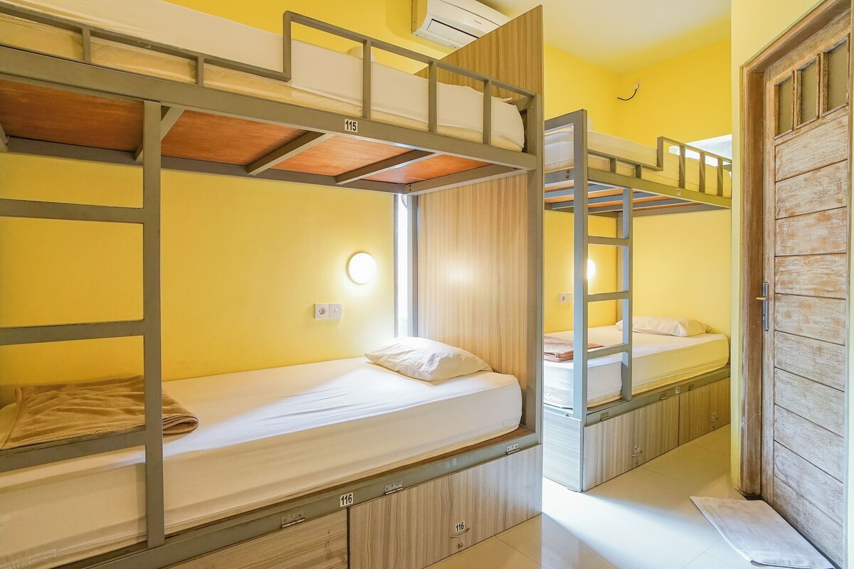 A bunk bed room with wooden bunk beds, a small window, and a door.