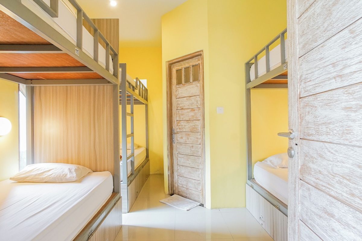 Una habitación con literas, una puerta de madera y un piso blanco.