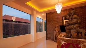 A spacious room with large windows, a chandelier, and a statue on a pedestal. - Kememai Hostel (Ubud)