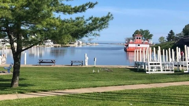 A waterfront park with a boat dock, picnic tables, and a white fence. - 'Stones Throw' Lakeside Home - Walk to Marina + Town + Assoc Beach (New Buffalo)