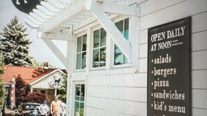 A restaurant sign with a dog logo and a list of daily offerings like salads, burgers, and pizza. - 'Stones Throw' Lakeside Home - Walk to Marina + Town + Assoc Beach (New Buffalo)