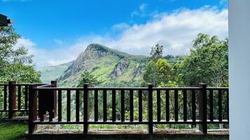 A balcony with a view of a mountain and greenery.