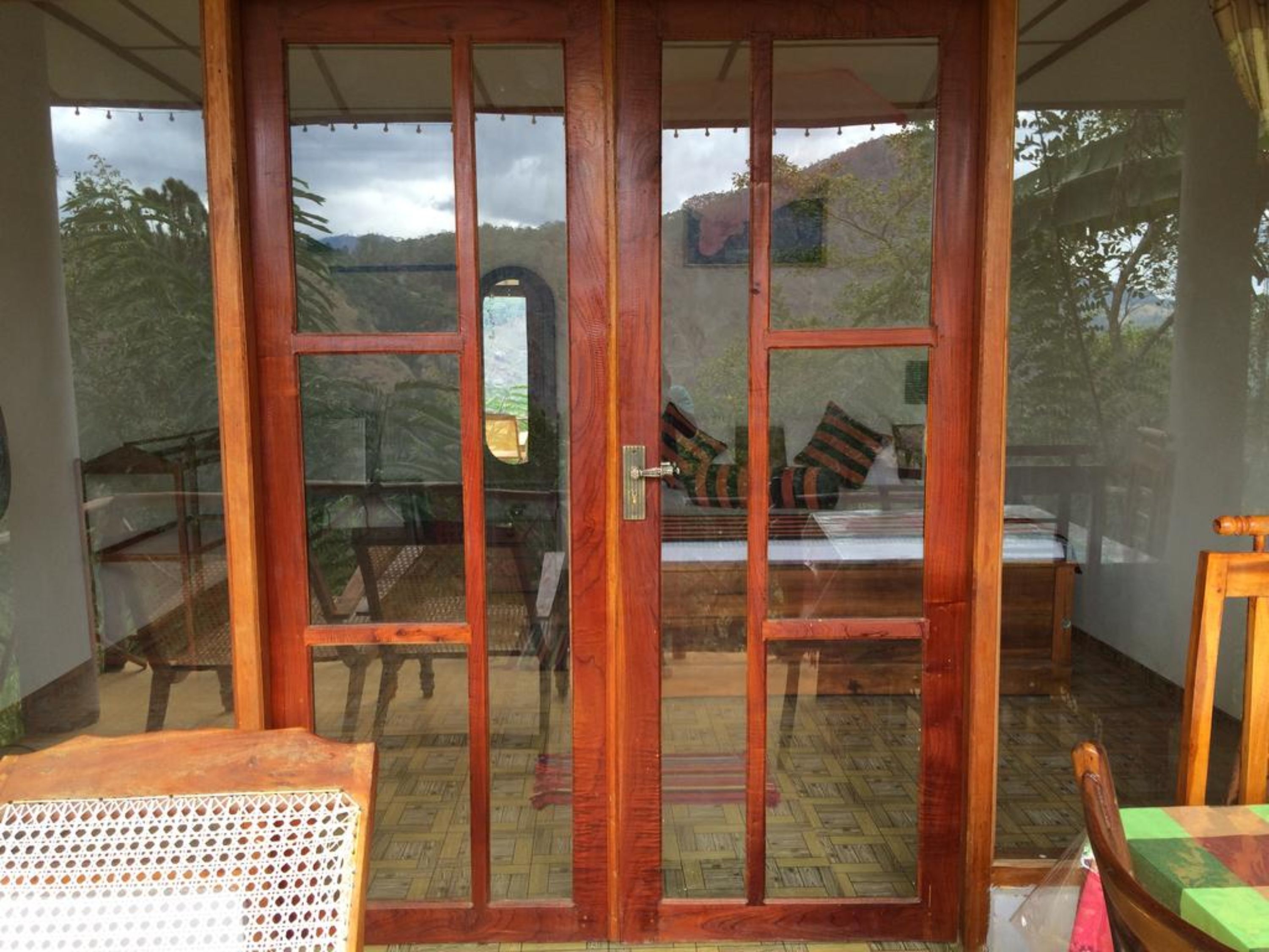 A room with a sliding glass door leading to a balcony with a view of trees and hills.