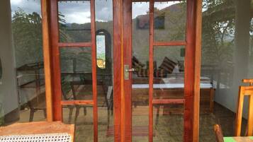 A room with a sliding glass door leading to a balcony with a view of trees and hills.