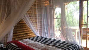 Een kamer met een bed, een hemelbed en uitzicht op de omgeving.