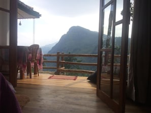 A room with a wooden floor, a view of a mountain, and a wooden railing. - Ella Ridge View (Ella)