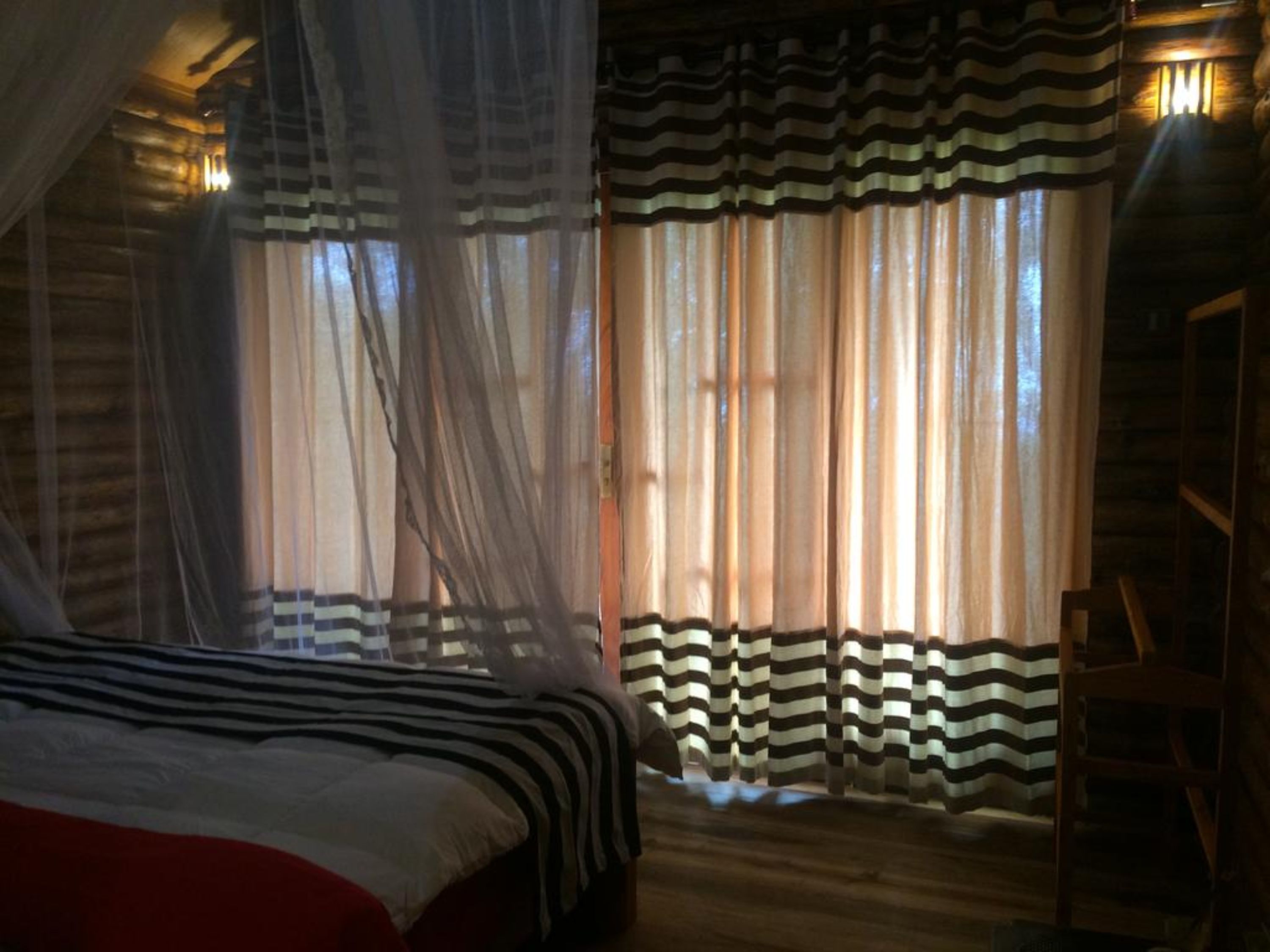Una habitación con una cama, cortinas y una silla.