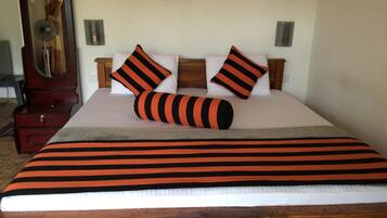 A neatly made bed with striped bedding, two pillows, and a bedside table with a lamp.