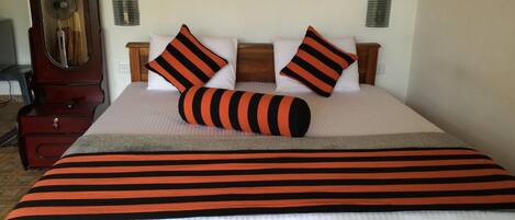 A neatly made bed with striped bedding, two pillows, and a bedside table with a lamp.