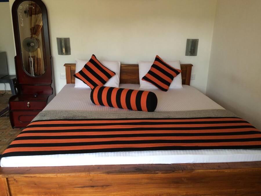 A neatly made bed with striped bedding, two pillows, and a bedside table with a lamp.
