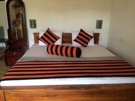 A neatly made bed with striped bedding, two pillows, and a bedside table with a lamp.