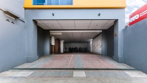 A modern building entrance with a tiled floor, a yellow and grey facade, and a sign for 'Sarkari Residency'. - Hotel O Sarkawi Residence (Jakarta)