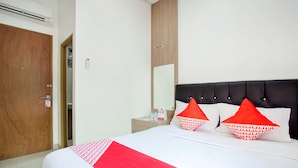 A hotel room with a bed, a wooden door, a nightstand, and a mirror. - Hotel O Sarkawi Residence (Jakarta)