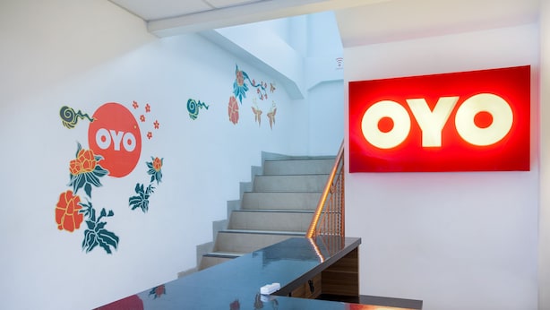A staircase with a glass handrail and a wall with 'OYO' branding and floral decorations. - Hotel O Sarkawi Residence (Jakarta)