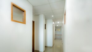A clean, well-lit hallway with white walls and a tiled floor, leading to a room with a patterned wall and a railing. - Hotel O Sarkawi Residence (Jakarta)