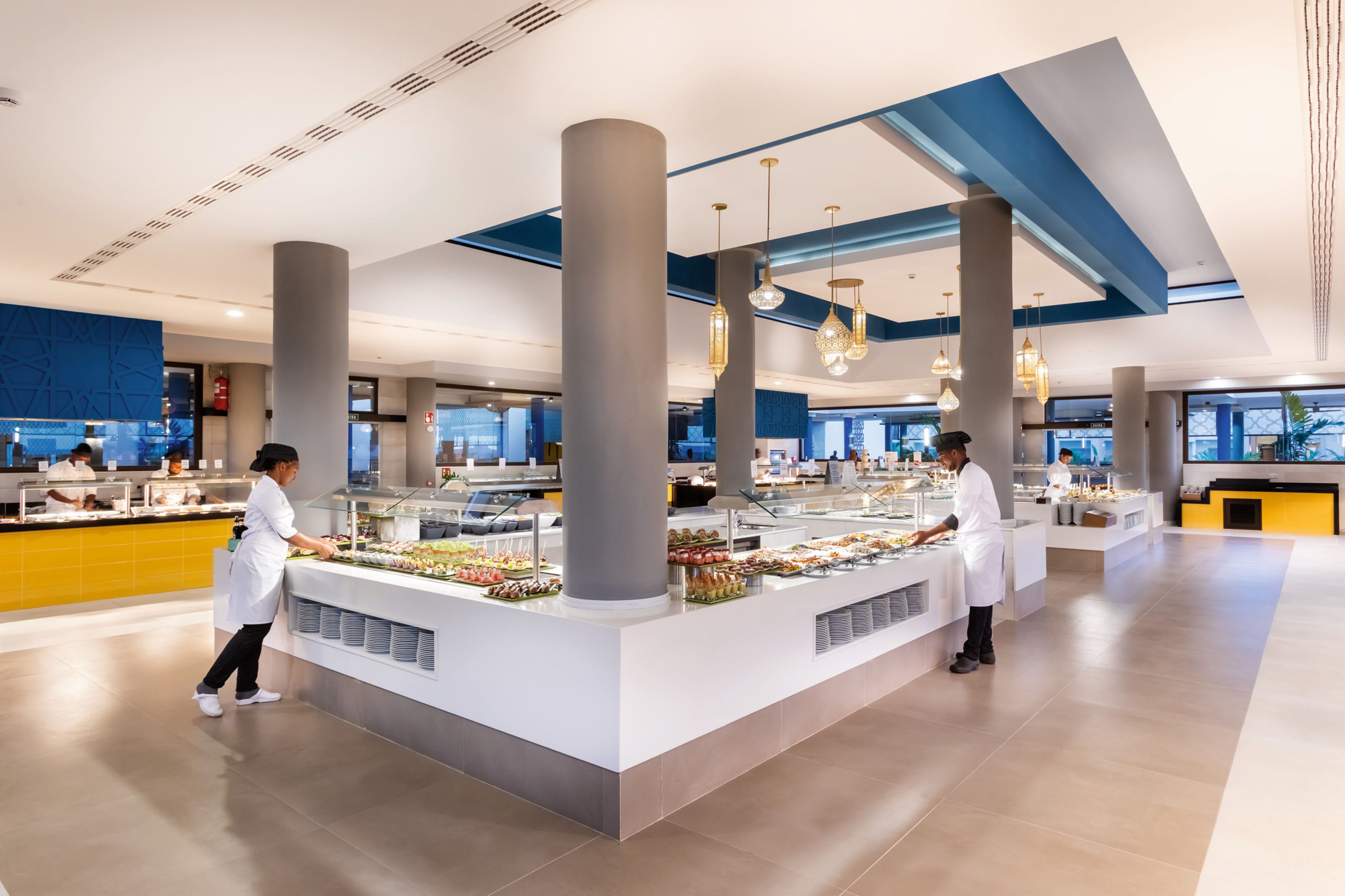 Ein modernes Buffet mit mehreren Speiseausgaben, großen Säulen und hängenden Pendelleuchten.