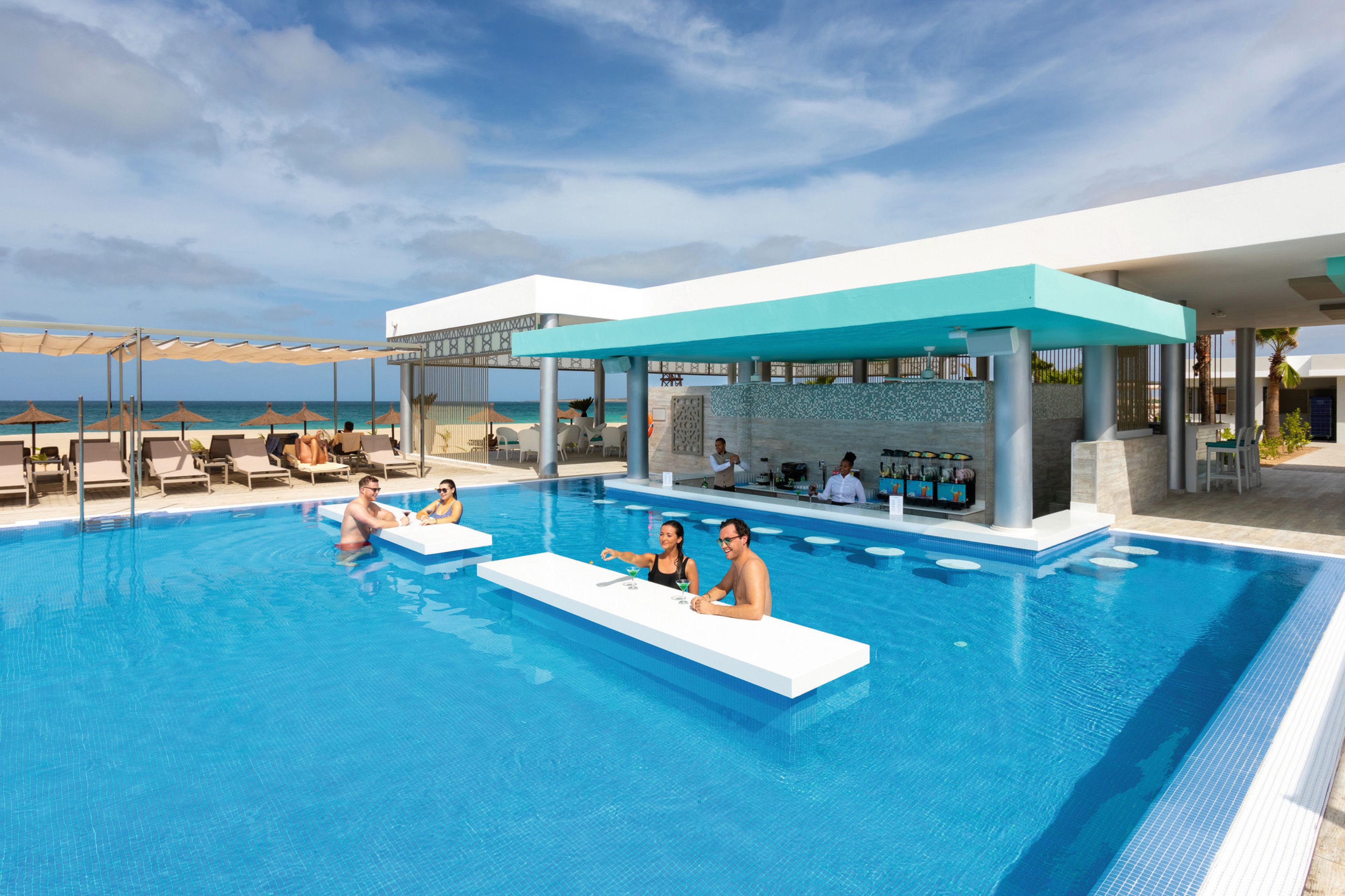 Una piscina con sillones de descanso y una zona de bar.