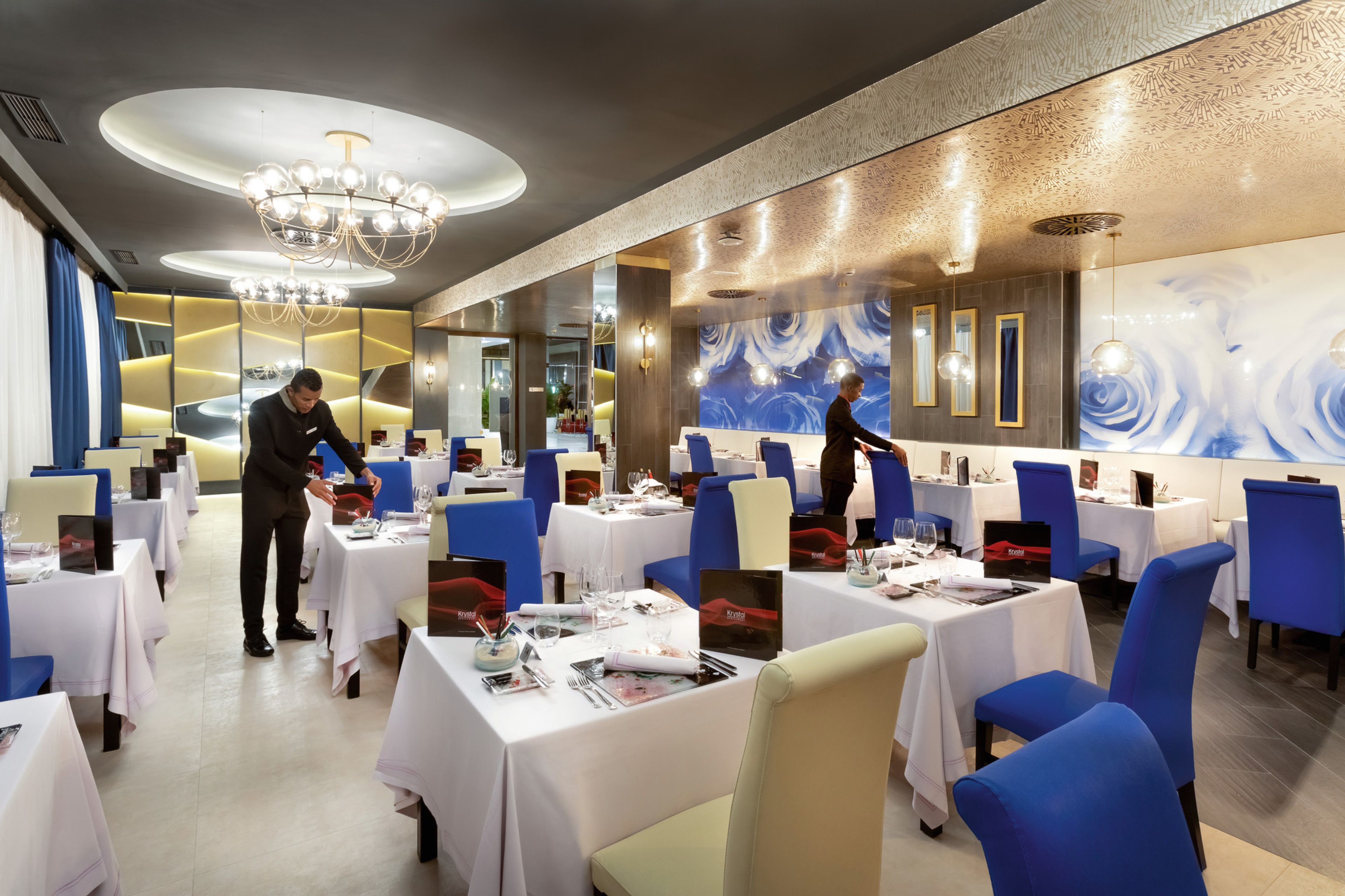 A restaurant with tables set for dining, a chandelier, and a modern interior design.