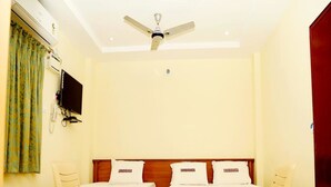 A hotel room with two beds, a ceiling fan, a TV, and a small table. - Hotel Shubhanga Residency (Srikalahasti)