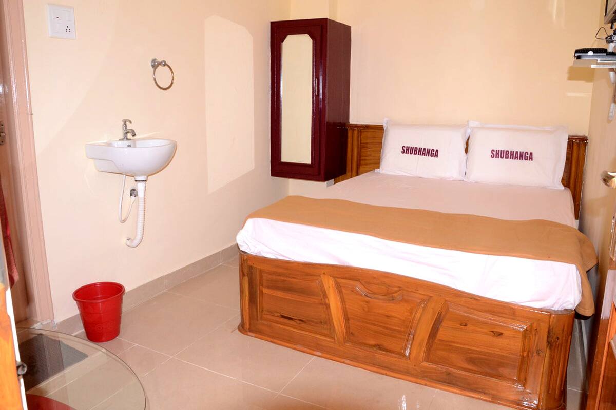 A bedroom with a wooden bed, a white sink, and a mirror.