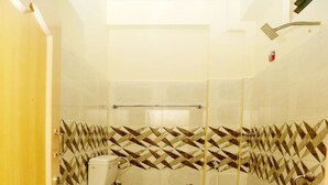 A small bathroom with a toilet, a shower, and a water heater. - Hotel Shubhanga Residency (Srikalahasti)