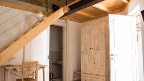 Una habitación con una escalera de madera, un armario de madera y una pequeña mesa con una silla.