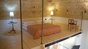 Una habitación con cama, una mesita, una silla y una lámpara.