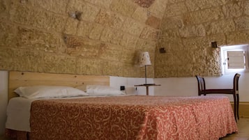 Une chambre à coucher avec un grand lit, une tête de lit en bois, une petite table avec une lampe et une chaise.