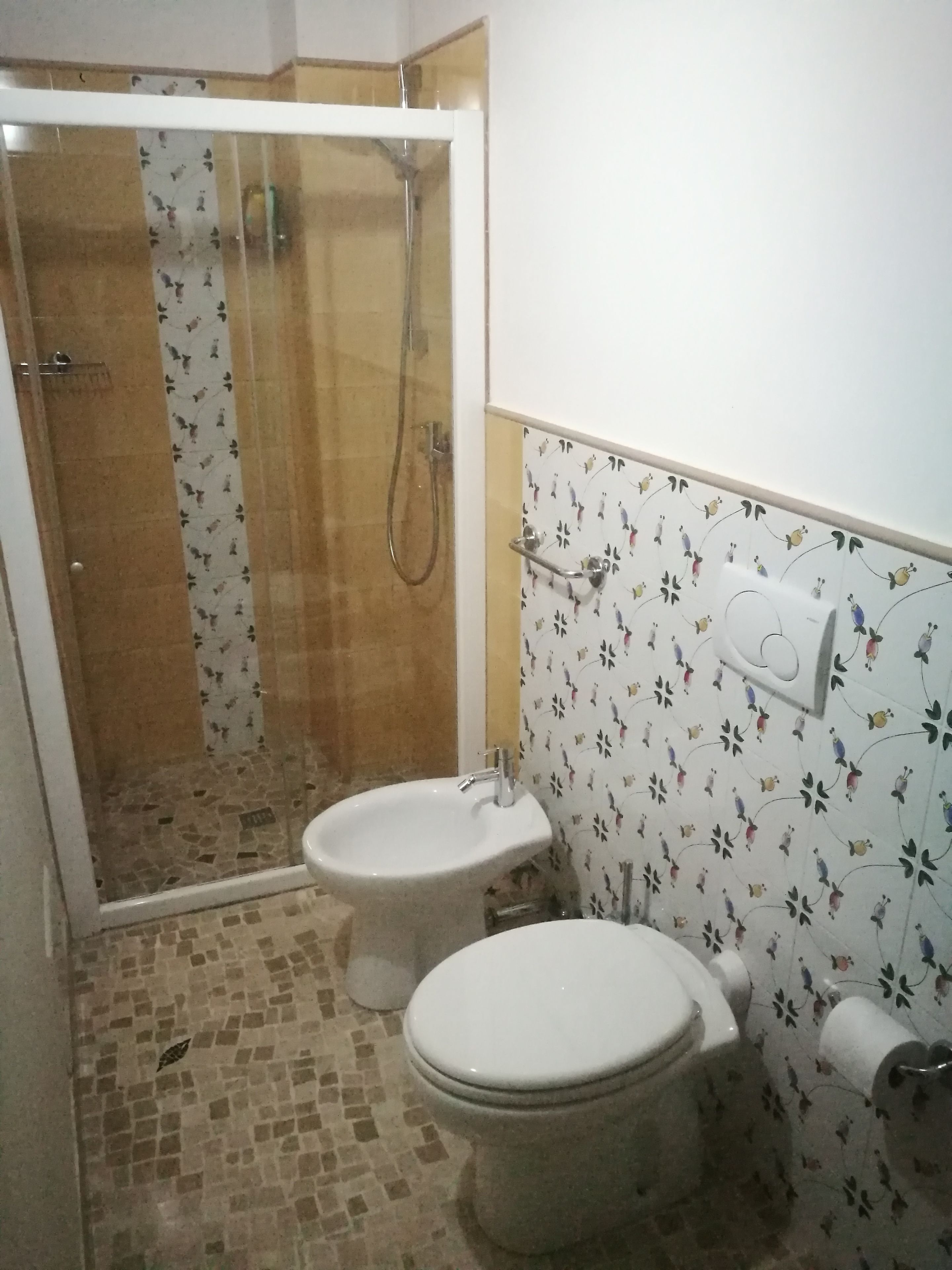 Un baño con ducha, dos inodoros, un lavabo y un dispensador de papel higiénico.