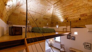 Una habitación rústica en el ático con una cama tipo litera, un escritorio pequeño y un radiador.