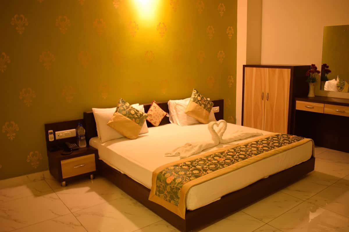 A hotel room with a bed, nightstands, a dresser, and a mirror.