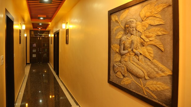A hallway with a marble floor, a ceiling with recessed lighting, and a large wall-mounted sculpture.
