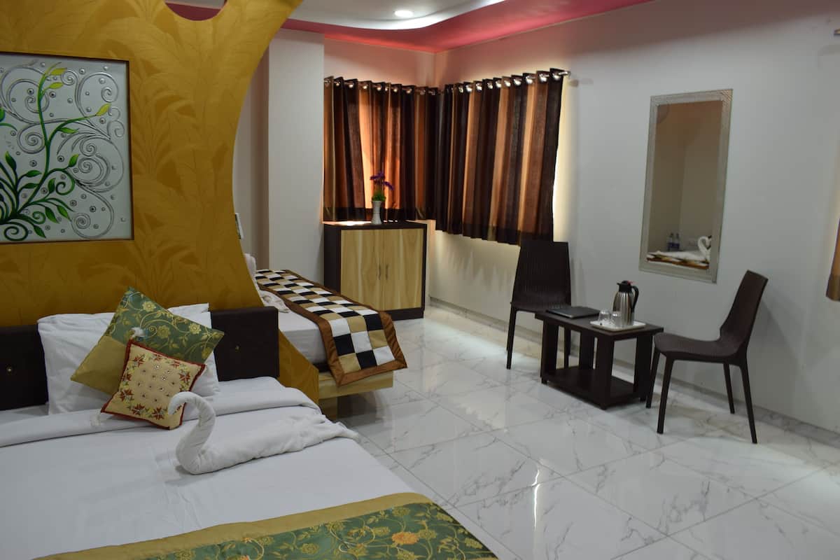A hotel room with a bed, a desk, a chair, a small table, a mirror, and a window with curtains.