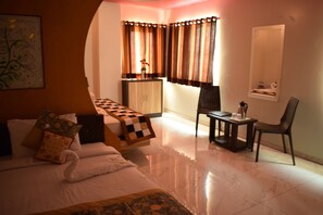 Una habitación de hotel con cama, una mesita, una silla, un armario y un espejo.