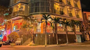 A modern hotel with a curved facade, multiple balconies, and a prominent illuminated sign. - Y Linh Hotel (Quy Nhon)