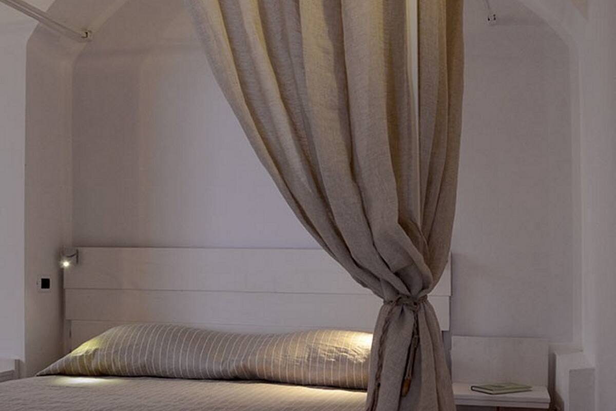 A bedroom with a bed, a nightstand, and a wall-mounted lamp.
