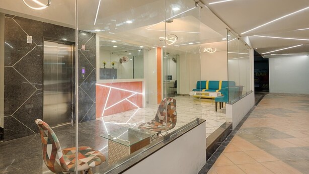 A modern reception area with a glass partition, a reception desk, and a seating area with sofas. - Hotel Vijay Fablis (Coimbatore)