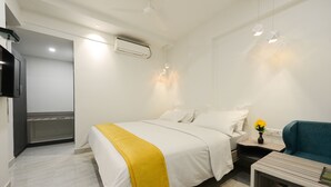A modern hotel room with a bed, bedside table, and a small seating area. - Hotel Vijay Fablis (Coimbatore)