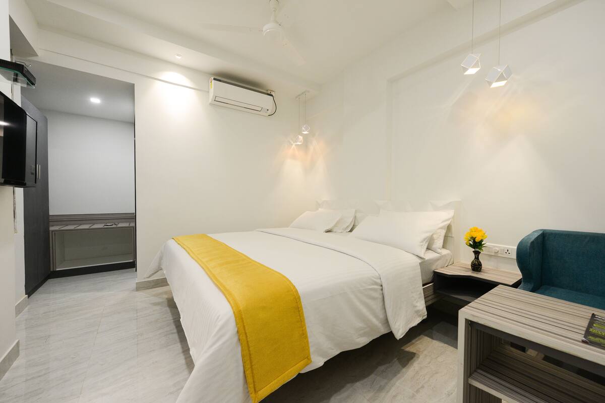 Une chambre d’hôtel moderne équipée d’un lit, d’une table de chevet et d’un petit coin salon.
