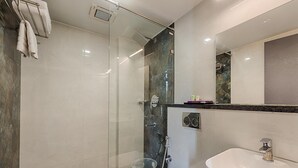 A modern bathroom with a glass-enclosed shower, a white toilet, and a sink with a marble countertop. - Hotel Vijay Fablis (Coimbatore)